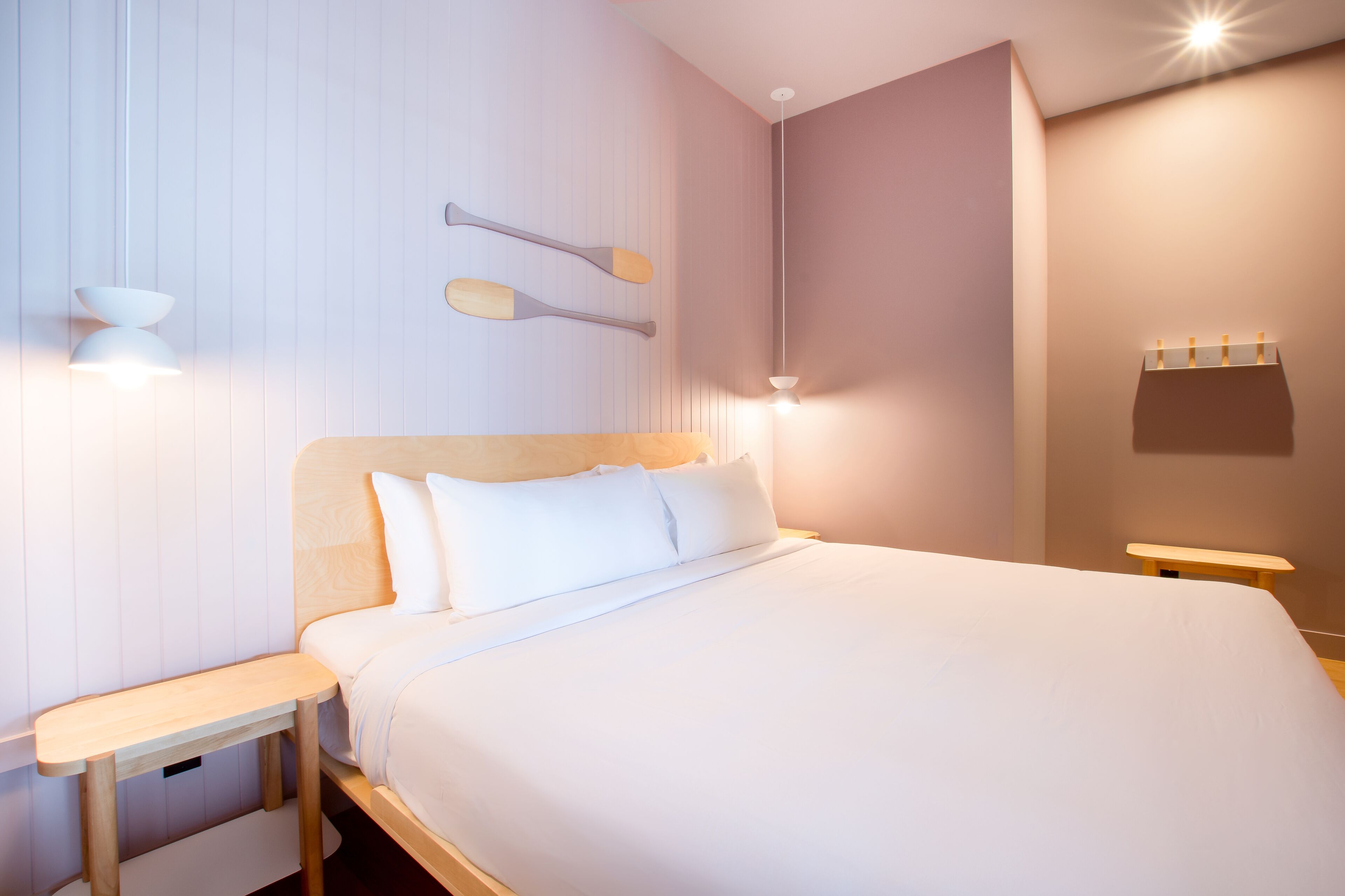 A neatly arranged bedroom with a large bed, bedside tables, and wall-mounted lighting.