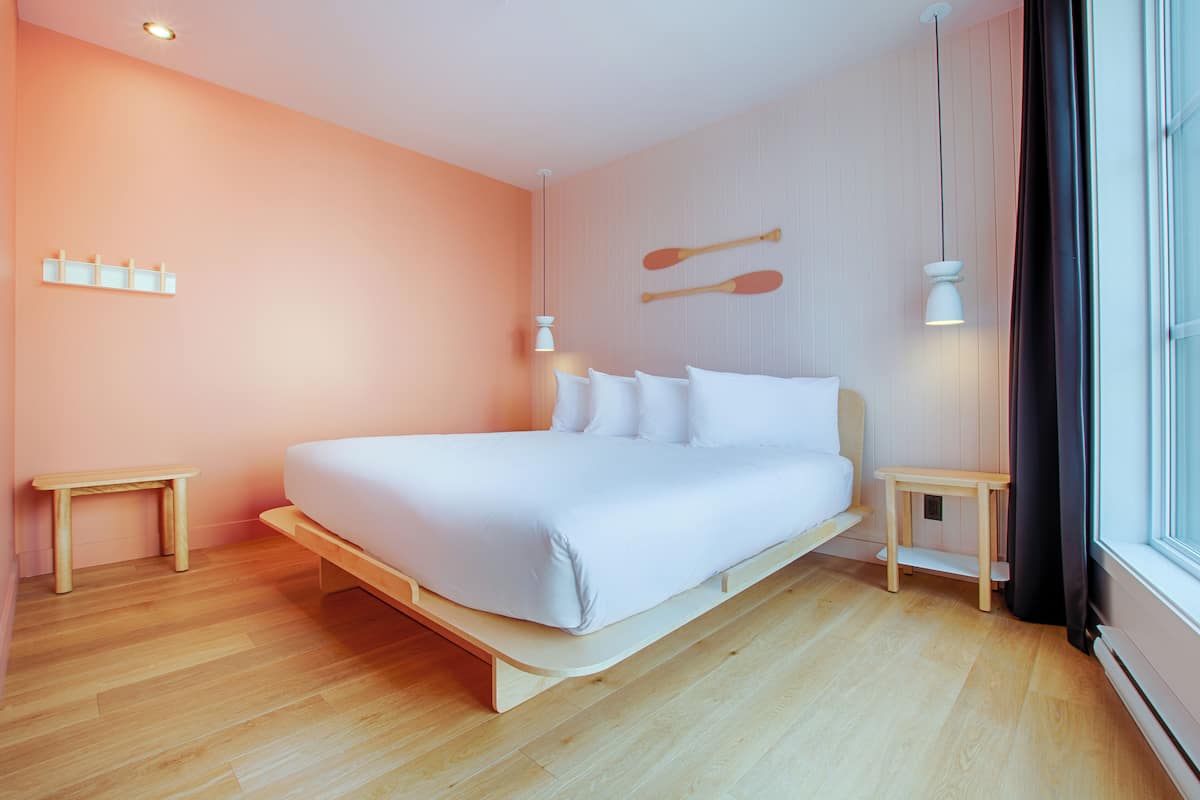 A modern bedroom with a wooden bed, two bedside tables, and a wall-mounted light fixture.