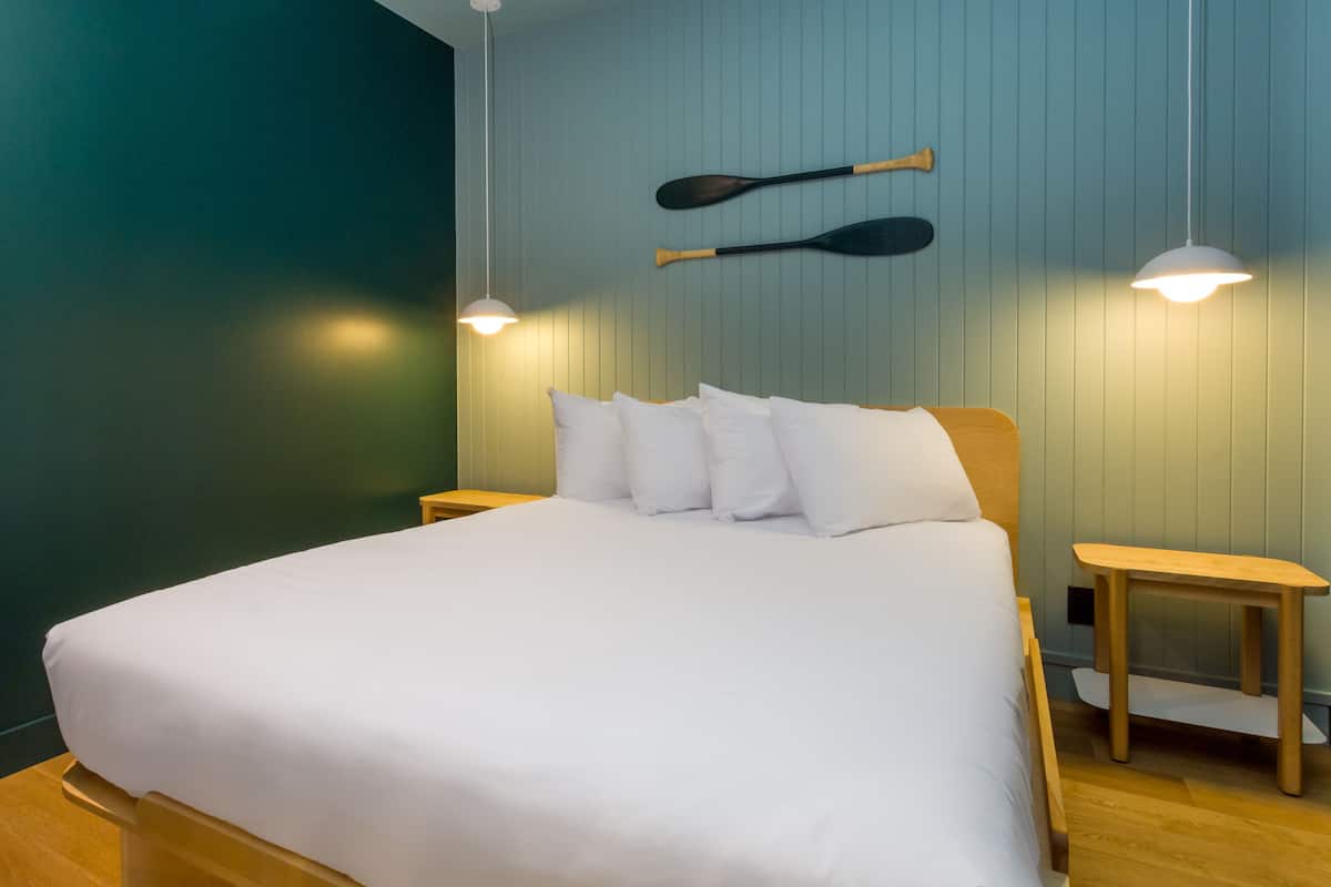 A neatly made bed with white bedding, wooden headboard, and two bedside tables with lamps.