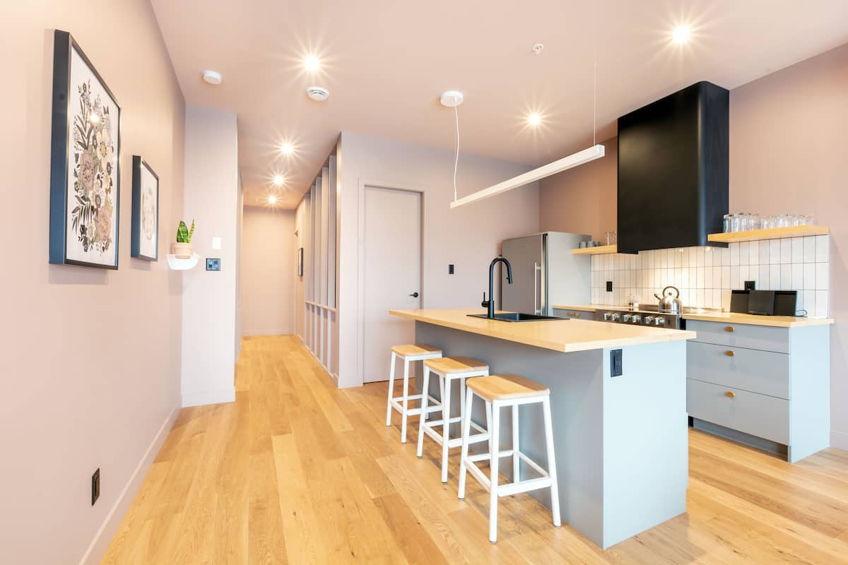 A modern kitchen with a central island, bar stools, and a built-in oven.