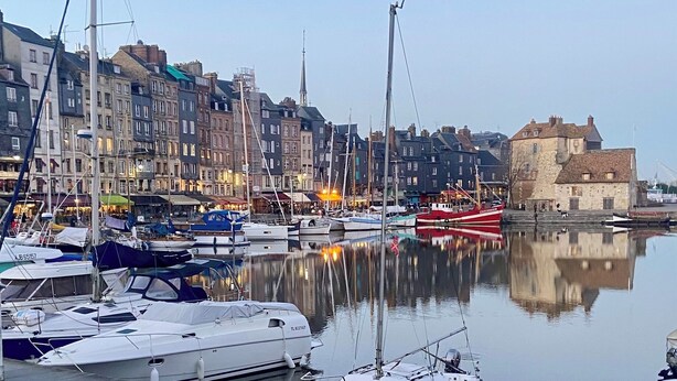 A marina with boats docked, a historic building, and a clear sky.