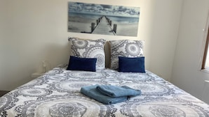 A bed with a patterned bedspread, two pillows, and a folded blanket.
