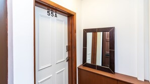 Ein Flur mit einer weißen Tür mit der Aufschrift '55A' und einer hölzernen Bank.