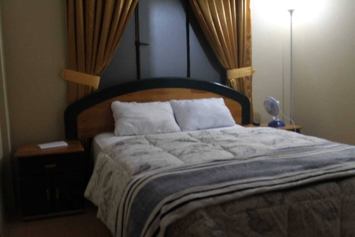 A neatly made bed with a wooden headboard, a bedside table with a lamp, and a nightstand.