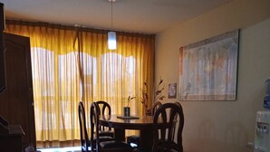 A dining area with a wooden table and chairs, a water dispenser, and a red stool. - Callao Backpacker - Adults Only (Callao)