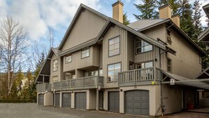 A multi-story building with a balcony, multiple garage doors, and a sign indicating no parking. - Luxury 2BR/2BA – Next to slopes, Private Garage (Whistler)