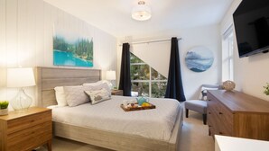 A bedroom with a bed, bedside tables, a dresser, a TV, and a window with curtains. - Luxury 2BR/2BA – Next to slopes, Private Garage (Whistler)