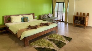 A bedroom with a bed, a bench, a fan, and a small table. - 104 - Ocean View - La Mer Beach House (Revdanda)