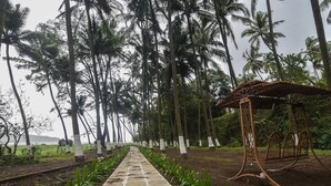A pathway lined with palm trees and a metal structure. - 104 - Ocean View - La Mer Beach House (Revdanda)