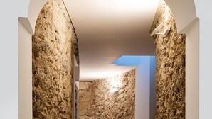 A hallway with textured stone walls, a tiled floor, and a small golden object on a pedestal. - Private Villa with Jacuzzi, Terraces, Sea View and Breakfast (Amalfi)