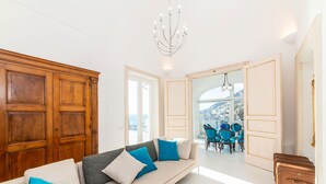 A modern living room with a sofa, a dining area with chairs, and a view of a mountainous landscape through large windows. - Private Villa with Jacuzzi, Terraces, Sea View and Breakfast (Amalfi)