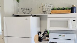 A compact kitchen with a refrigerator, microwave, and stove.