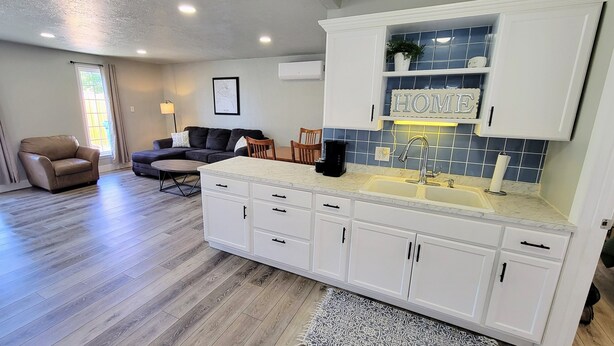 A modern kitchen with white cabinets, a marble countertop, and a built-in sink.