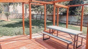 A wooden deck with a bench and a pergola structure.