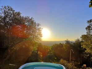 Ein Schwimmbad, umgeben von Bäumen, mit freiem Blick auf den Sonnenuntergang im Hintergrund.