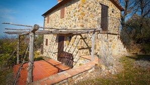 A stone building with a wooden balcony and a staircase leading to the entrance. - Secluded location and absolute tranquility in Tuscany (Monticello Amiata)