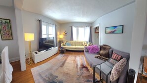 A living room with a sofa, a TV, a lamp, and a rug.