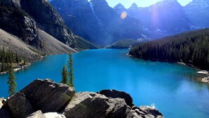 A mountainous landscape with a clear blue lake, rocky terrain, and dense forests. - WindTower Resort @ Cozy Hotel Room (Canmore)
