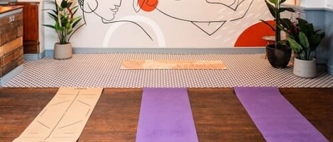 A yoga studio with wooden flooring, a patterned rug, and three yoga mats.