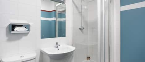 A modern bathroom with a white sink, a glass shower enclosure, and a mirror above the sink.