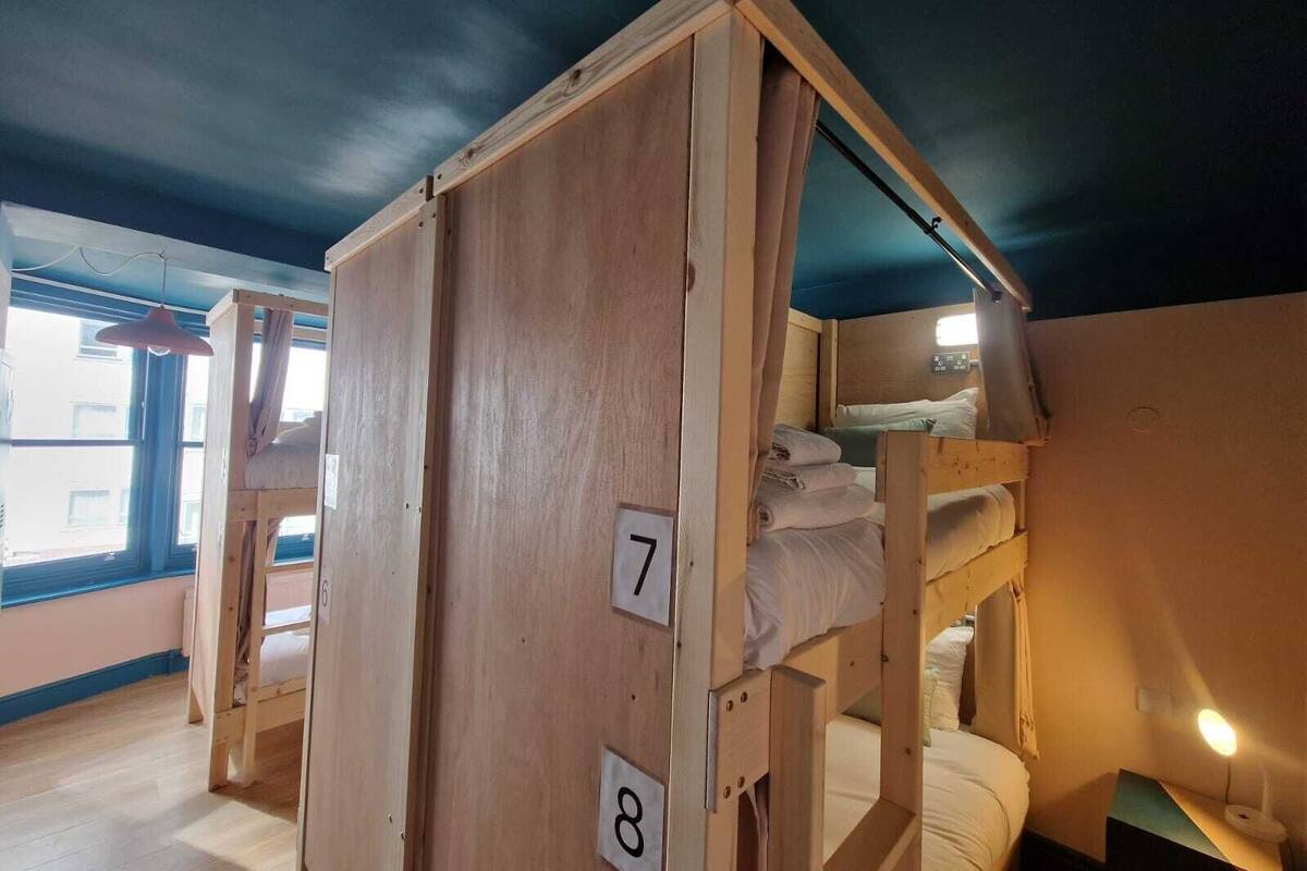 A wooden bunk bed room with numbers 7 and 8 on the side, a window, and a hanging light fixture.