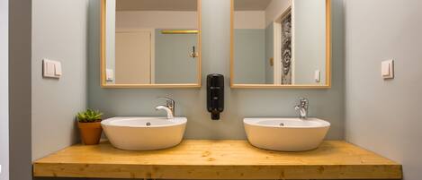 A bathroom with two sinks, a wooden countertop, and a mirror above each sink.