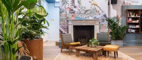 A cozy living room with a fireplace, comfortable seating, and a large potted plant.