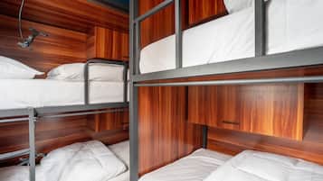 Habitación con literas, paneles de madera y barandillas de metal.