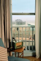 A room with a view of a pier and beach, a wooden table with a radio, and a striped pillow.