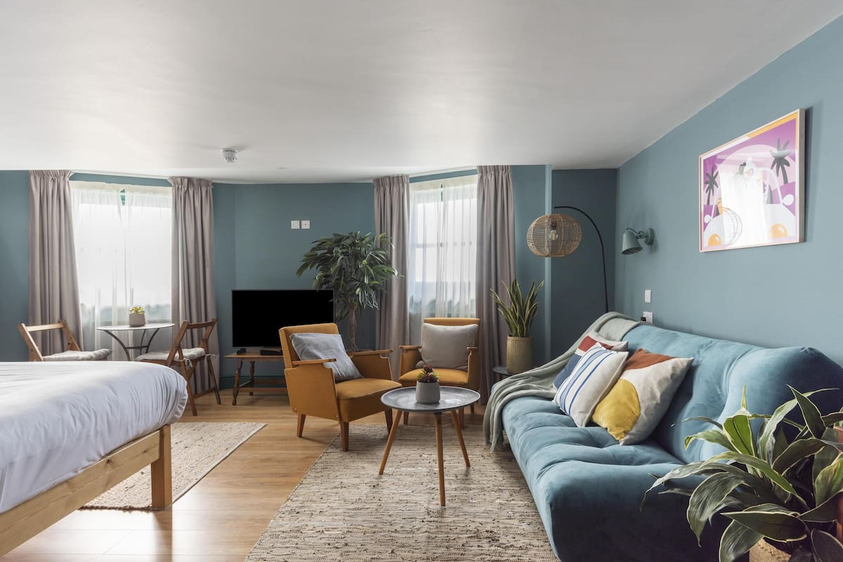 A modern living room with a sofa, armchairs, a coffee table, and a TV.