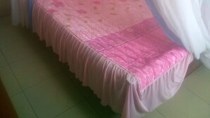 A single bed with a pink bedspread and a wooden headboard, surrounded by sheer white curtains. - Kea Guest House (Nairobi)