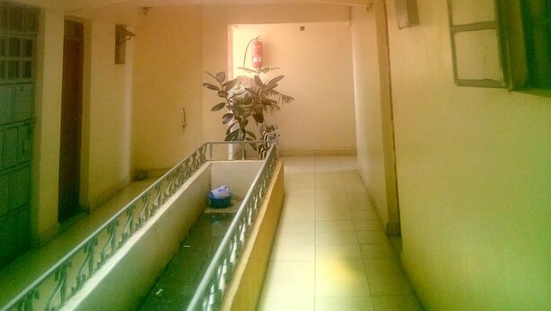 A corridor with a glass balustrade, a fire extinguisher, and a potted plant. - Kea Guest House (Nairobi)