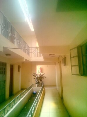 A corridor with a glass balustrade, a fire extinguisher, and a potted plant. - Kea Guest House (Nairobi)