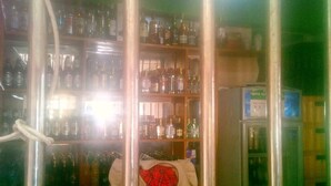 A bar area with shelves stocked with various bottles, a refrigerator, and a counter with a menu. - Kea Guest House (Nairobi)