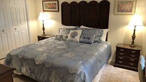 Une chambre à coucher comprenant un lit, deux tables de chevet, une commode et un ventilateur de plafond.