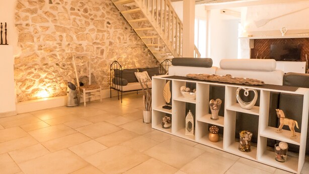 A living room with a stone wall, a staircase, a sofa, and shelves with decorative items.
