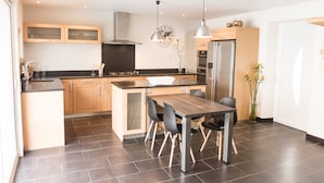 A modern kitchen with wooden cabinets, a central island, and a dining table with chairs.