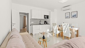 A modern living room with a sofa, a glass coffee table, and a dining area with chairs and a table. - 2bedroom apartment - ground floor (Vrvari)