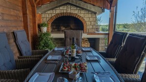 An outdoor dining area with a brick oven, wicker furniture, and a view of the landscape. - 2bedroom apartment - ground floor (Vrvari)