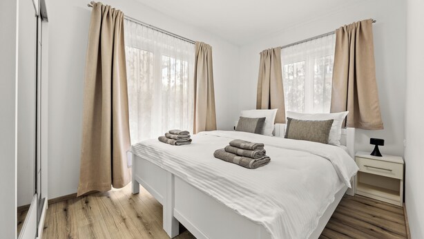 A modern bedroom with a large bed, two bedside tables, and a window with curtains. - 2bedroom apartment - ground floor (Vrvari)