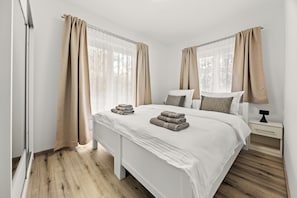 Un dormitorio moderno con una cama grande, dos mesitas de noche y una ventana con cortinas.