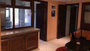 A modern kitchen with a wooden countertop and cabinets, a dining area with a round table and chairs, and a view through a window to the outside. - Appart Residence Al Menzah (Agadir)