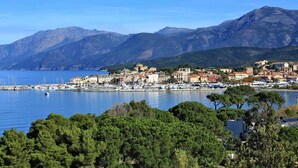 Uma cidade costeira com um porto de iates, edifícios e montanhas ao fundo.