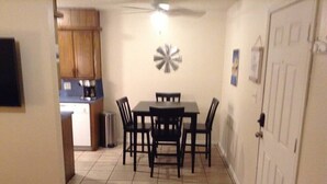 A dining area with a table and chairs, a ceiling fan, and a kitchen in the background. - Convenient 1-Bedroom Apartment Next to Fort Sill (Lawton)