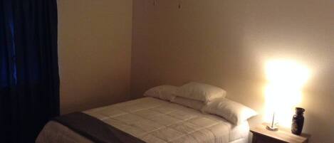 Une chambre à coucher avec un lit, une table de chevet, une lampe et un ventilateur de plafond.