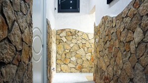 Un pasillo con paredes de piedra y una puerta que da a una habitación.