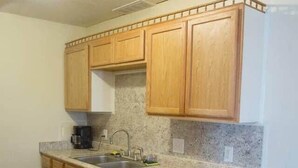 A kitchen with wooden cabinets, a granite countertop, a dishwasher, and a trash can.