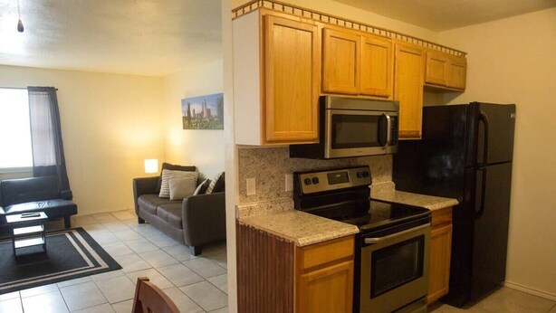 A compact kitchen with wooden cabinets, a built-in microwave, a stove, and a refrigerator.