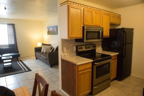 A compact kitchen with wooden cabinets, a stainless steel oven, a microwave, and a refrigerator. - 14% discount for 1 week 22% discount for 1 month (Lawton)