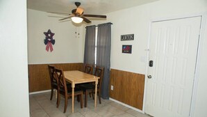 A dining area with a wooden table and chairs, a ceiling fan, and a door labeled "LAWTON."